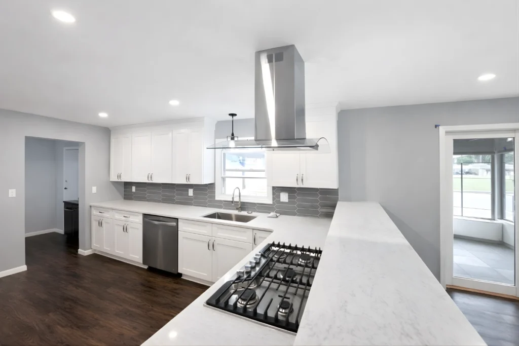 Completed modern kitchen remodeling project with white cabinets, island cooktop, and updated lighting in Berkeley Township, NJ.