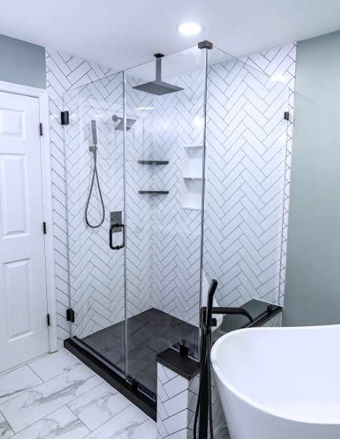 Frameless glass shower with herringbone tile and black fixtures